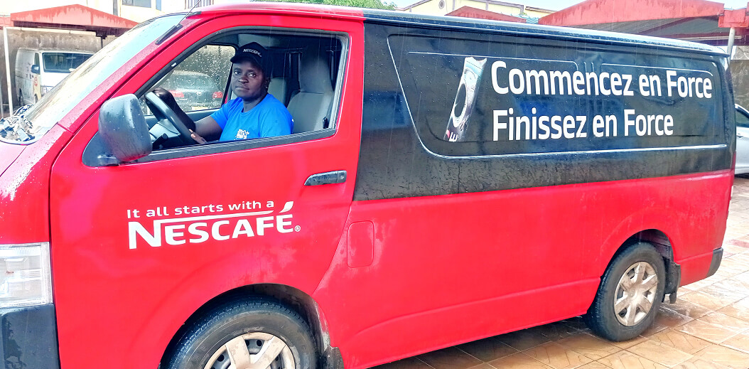 A red Nescafé delivery van parked with the slogan "Commencez en Force Finissez en Force" visible on its side.