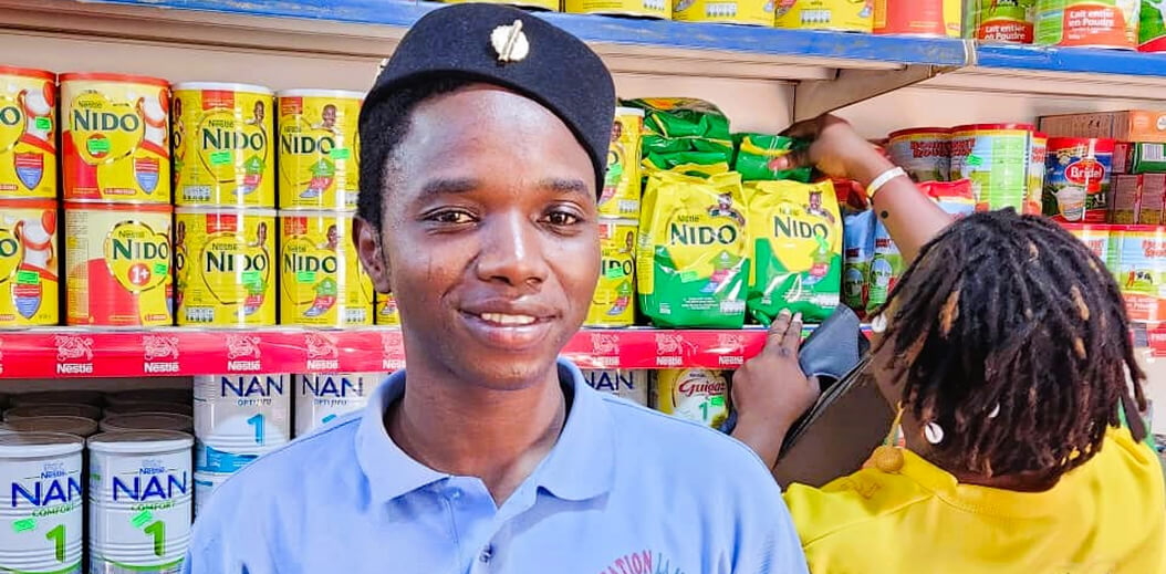 A person stands in front of shelves stocked with various Nestlé products, including Nido and NAN infant formula cans.