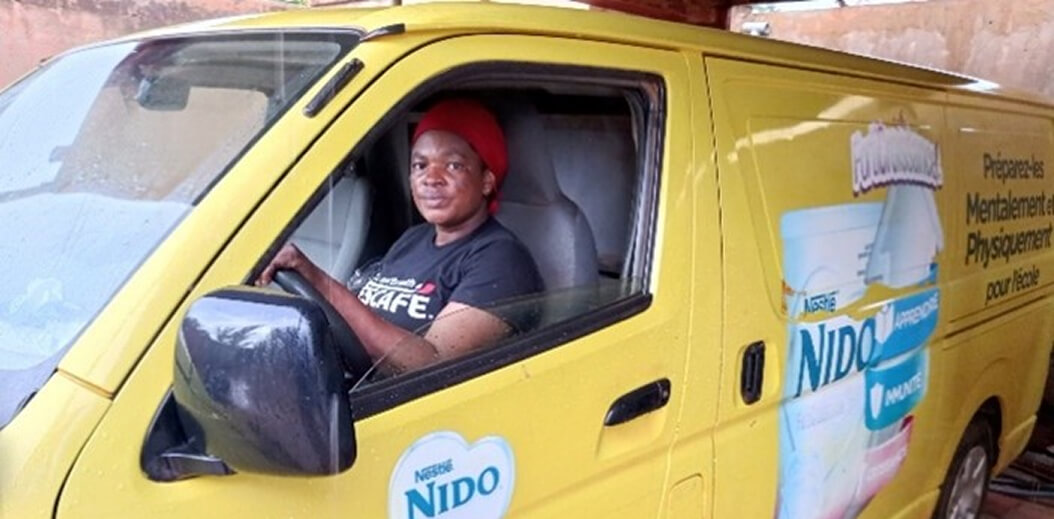 A person sits in the driver's seat of a bright yellow delivery van with Nestlé Nido branding