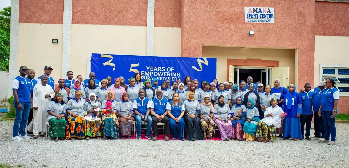 Group photo of diverse people celebrating 5 years of empowering rural retailers outside Amana Event Centre.
