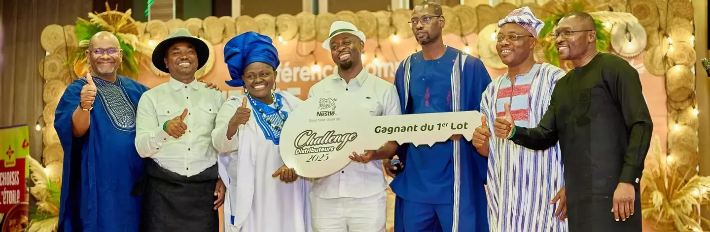 Group of men in traditional attire celebrate with a large prize key at an event, showcasing camaraderie and success.