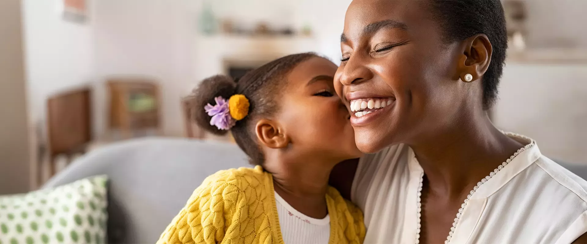 Young girl kissing smiling mother's cheek at home