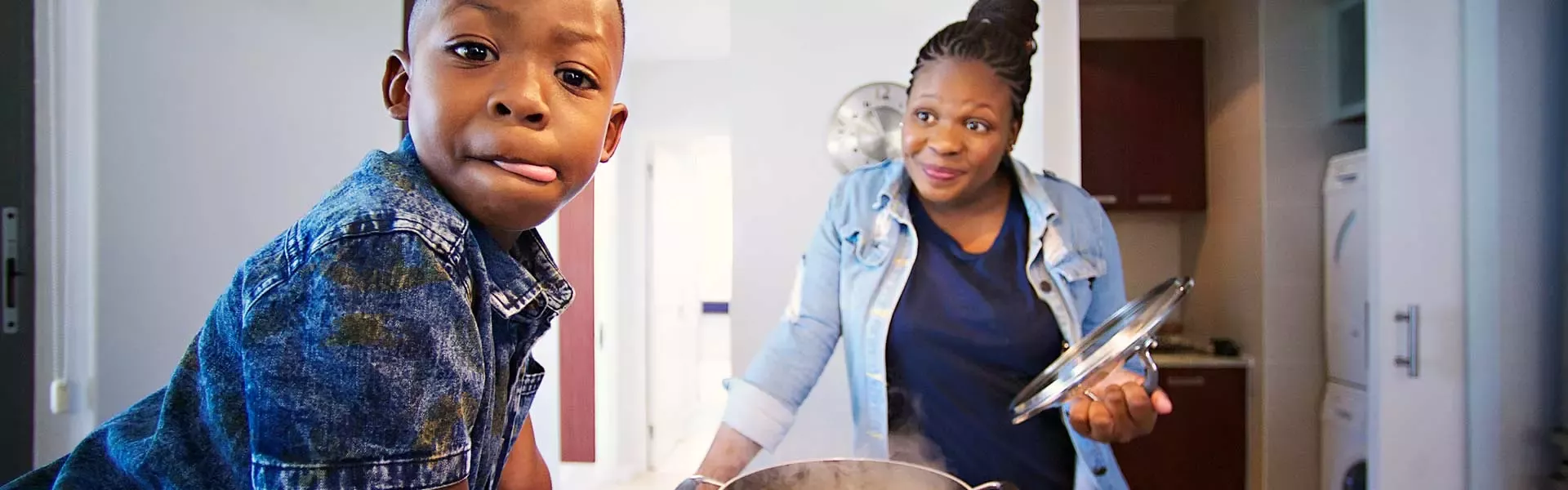 child and parent in kitchen as dinner cooks