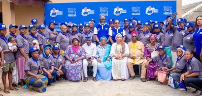 Group photo of participants in Nestlé program, wearing branded hats and shirts, gathered outdoors in front of a Nestlé backdrop.