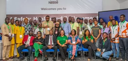 Group of diverse individuals gathered for a Nestlé event focused on safety, health, and environment, wearing name tags and green lanyards.