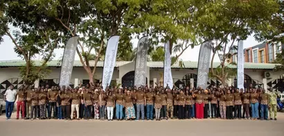 Large group of people standing outdoors in front of a building with Nestlé for Good banners and trees above them.