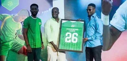 Three men presenting a framed green sports jersey with "U-13 Champions League 26" and signatures on it.