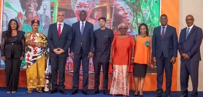 Group of nine formally dressed individuals standing in a line on a stage with a colorful backdrop.