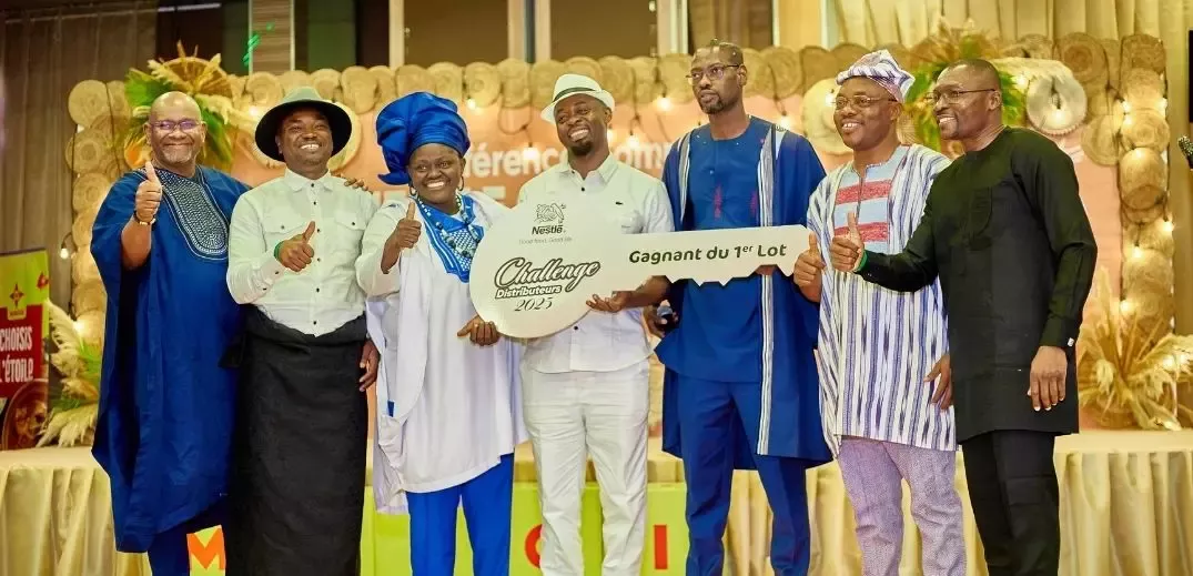 Group of men in traditional attire celebrate with a large prize key at an event, showcasing camaraderie and success.