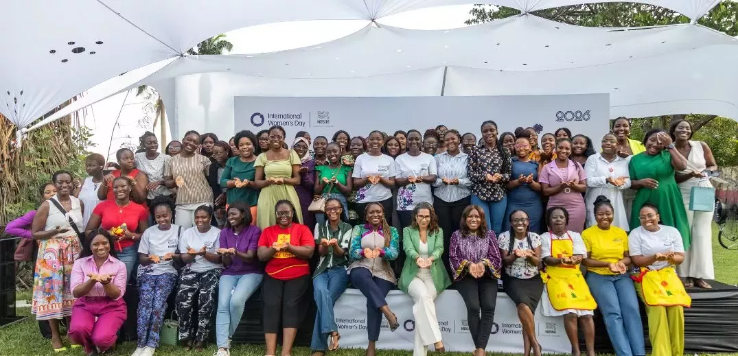Group photo of diverse women gathered outdoors under a canopy, celebrating International Women's Day 2026 with hands cupped
