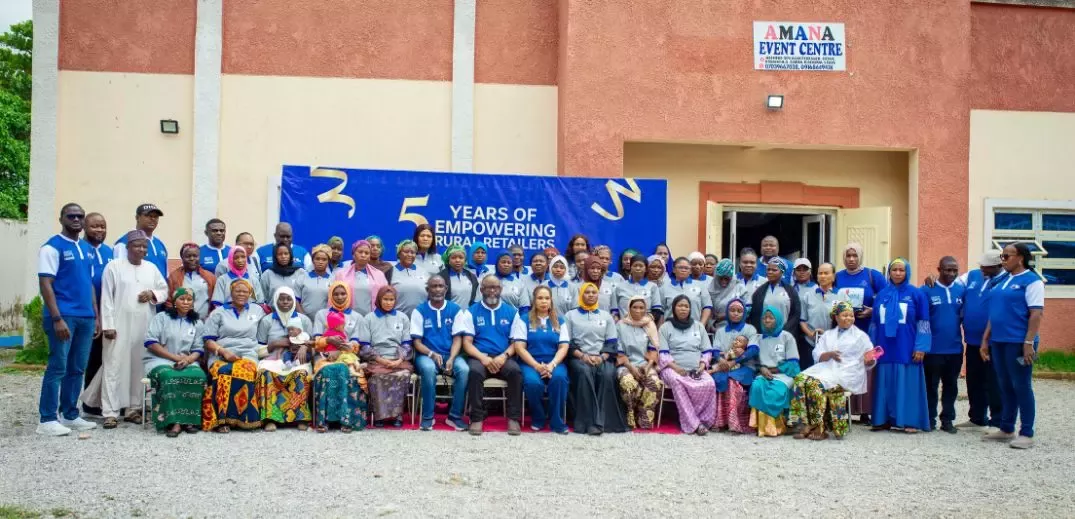 Group photo of diverse people celebrating 5 years of empowering rural retailers outside Amana Event Centre.